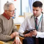 . A doctor discusses glaucoma with a patient in a hospital room, surrounded by medical equipment and a calming environment.