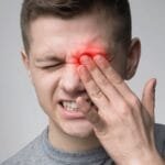 A man with conjunctivitis, featuring a red eye and a red spot on his face.