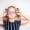 A little girl with glasses smiles while holding a purple eye patch for her lazy eye treatment
